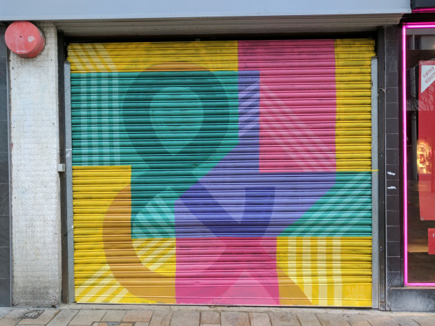 Shop shutters painted with colourful shapes and a giant ampersand